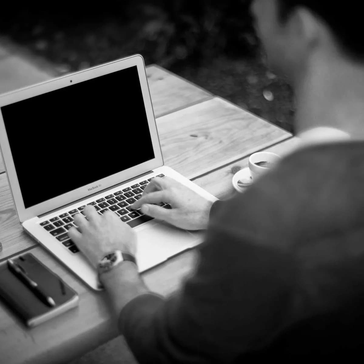 Une personne travaille sur un ordinateur portable, vue de dos.