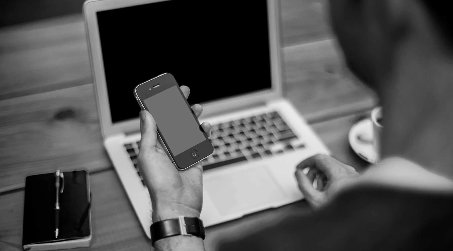 Mains posées près d'un ordinateur portable sur un plan de travail.
