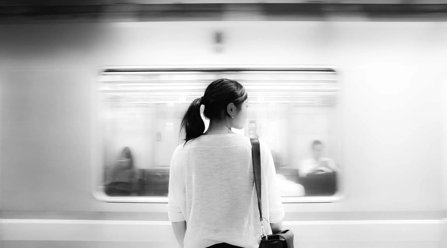 Une personne sur un quai regarde un train qui s'éloigne.