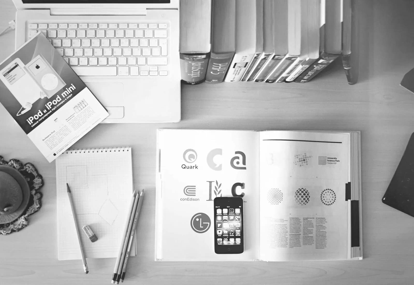 An open magazine, a keyboard and sheets of paper on a work surface.